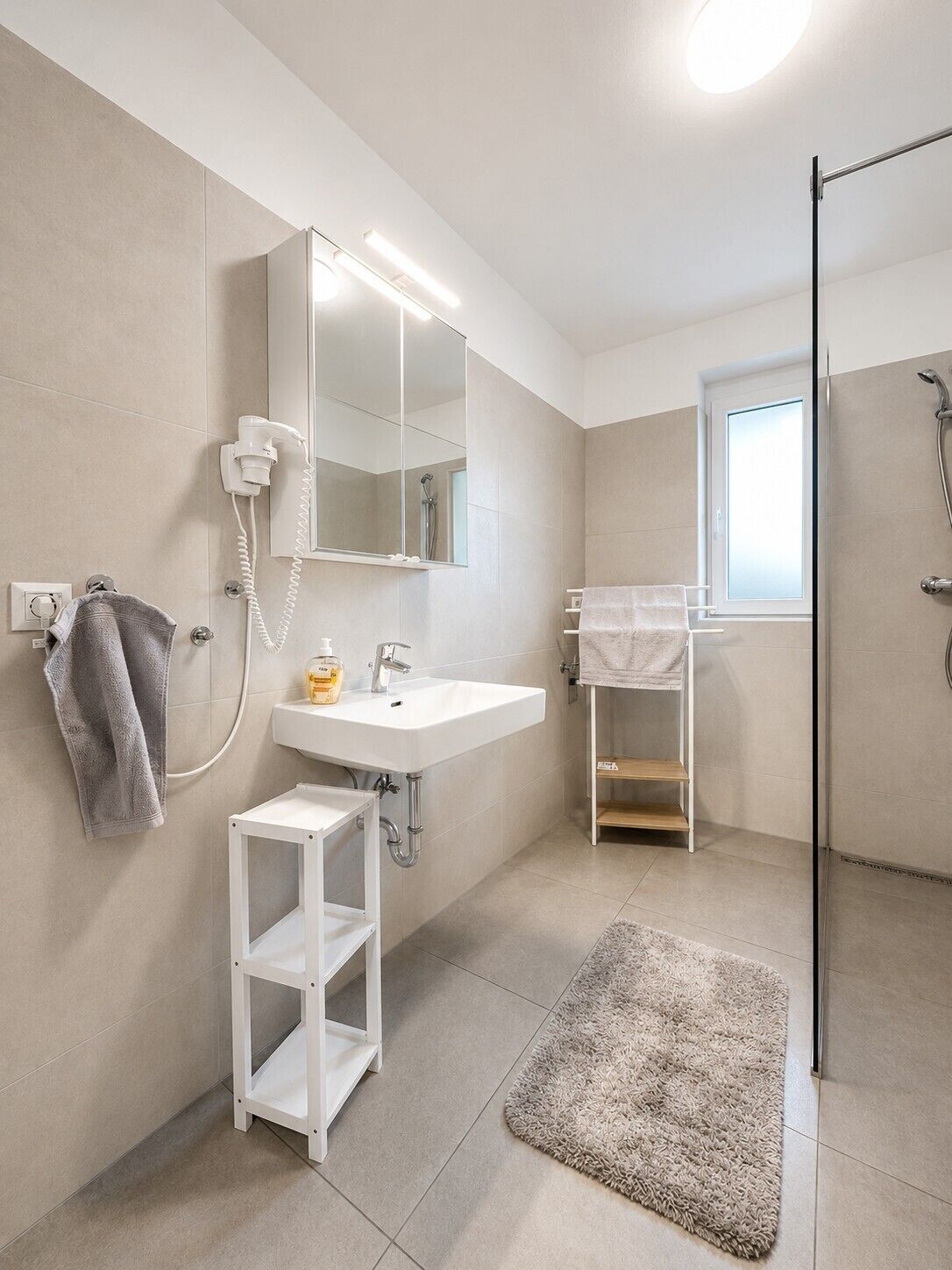 A modern bathroom with a white sink, mirror, and towel rack.