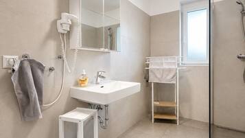 A modern bathroom with a white sink, mirror, and towel rack.