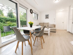 Una sala de estar moderna con un sofá, una mesa de comedor con sillas y una zona de cocina.