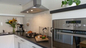 Una cocina moderna con armarios blancos, electrodomésticos de acero inoxidable y un reloj digital que marca las 15:26.