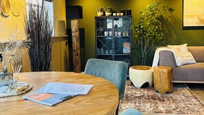 Una sala moderna con una mesa redonda de madera, un sofá y un aparador con objetos decorativos.