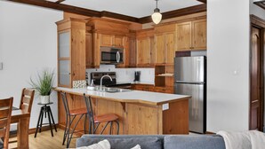 Une cuisine moderne avec des meubles en bois, un réfrigérateur en acier inoxydable et un coin bar.