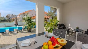 Uma varanda com uma mesa posta para o café da manhã, piscina e vista para casas.