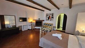 Un dormitorio con cama, televisor, chimenea y espejo.