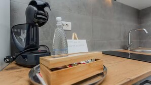 Ett modernt kök med en kaffemaskin, en vattenflaska och en trälåda på bänkskivan.