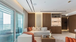 Ein modernes Wohnzimmer mit Sofa, Hocker, Couchtisch und Blick durch große Fenster.