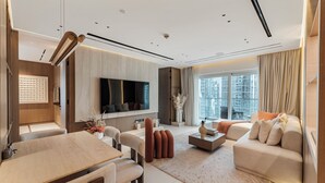 Ein modernes Wohnzimmer mit Flachbildfernseher, einem Essbereich und einer Sofagarnitur.