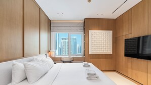 Ein modernes Hotelzimmer mit einem großen Bett, einem Flachbildfernseher, einem Fenster mit Blick auf die Stadt und Holzvertäfelung.