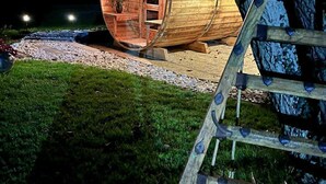 Una struttura a forma di botte in legno, con una porta, finestre, una scala e un vialetto sterrato.