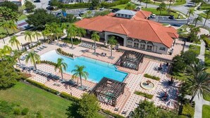 Luchtbeeld van een resort met een zwembad, palmbomen en een overdekt terras.
