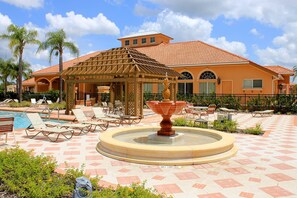 A resort pool area with lounge chairs, a gazebo, and a fountain. - 4BR house sleeps 11 with private pool (Kissimmee)