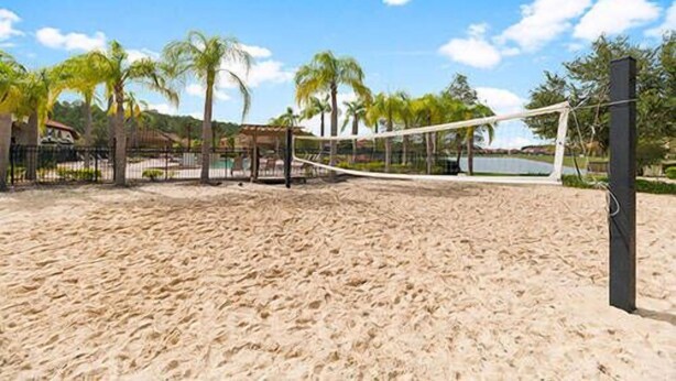 Een strandvolleybalveld met een net, palmbomen en een gebouw op de achtergrond.