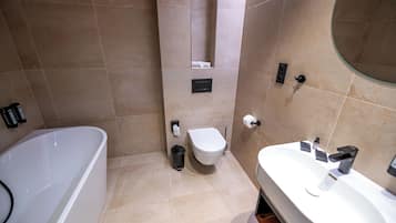 A modern bathroom with a bathtub, toilet, and sink.