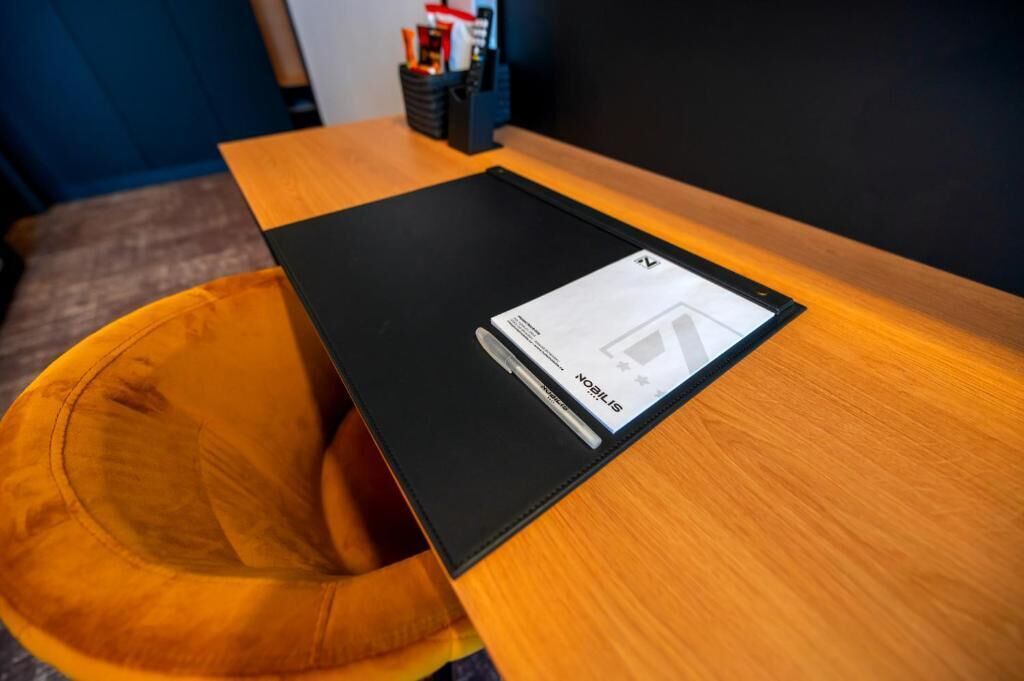 A black folder on a wooden table with a cushion.