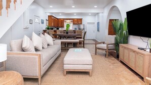 A modern living room with a sofa, ottoman, and a flat-screen TV.