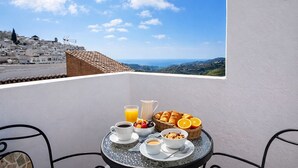 Ein Balkon mit Frühstücksangebot, freier Blick auf eine Stadtlandschaft und ein Tisch mit Stühlen.