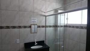 Une salle de bain avec une douche à parois de verre, un lavabo avec un miroir et un mur carrelé agrémenté d’une bordure décorative.
