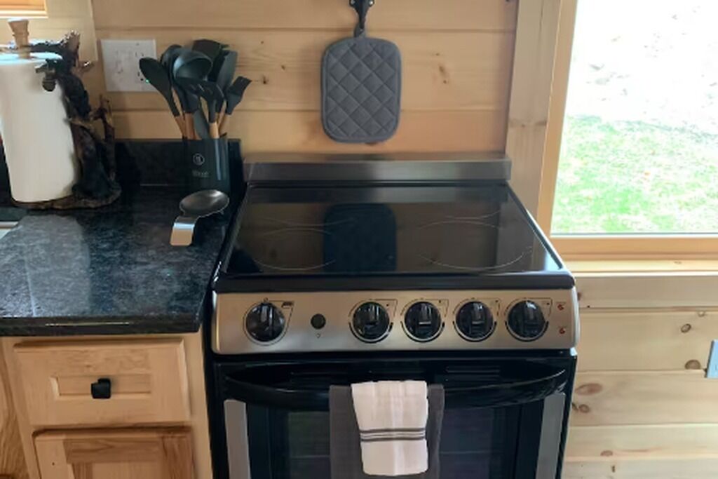 Une cuisine équipée d’une cuisinière, d’un four et de meubles de rangement en bois.