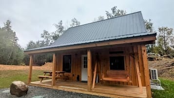 A wooden cabin with a porch, a door, and a window.