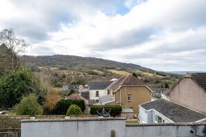 A residential area with houses, a hill in the background, and a cloudy sky.