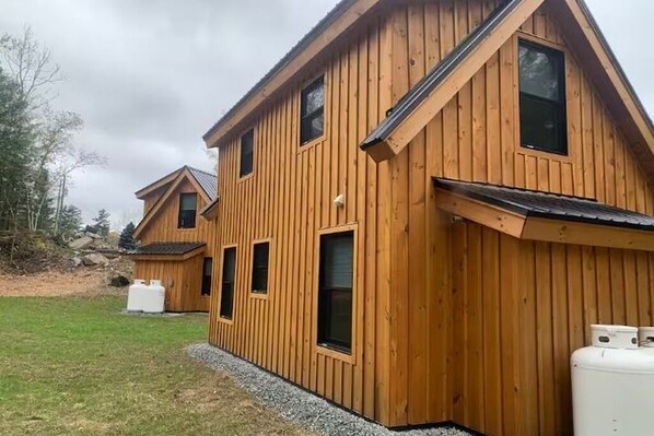 A wooden house with a sloped roof, multiple windows, and a gravel driveway.