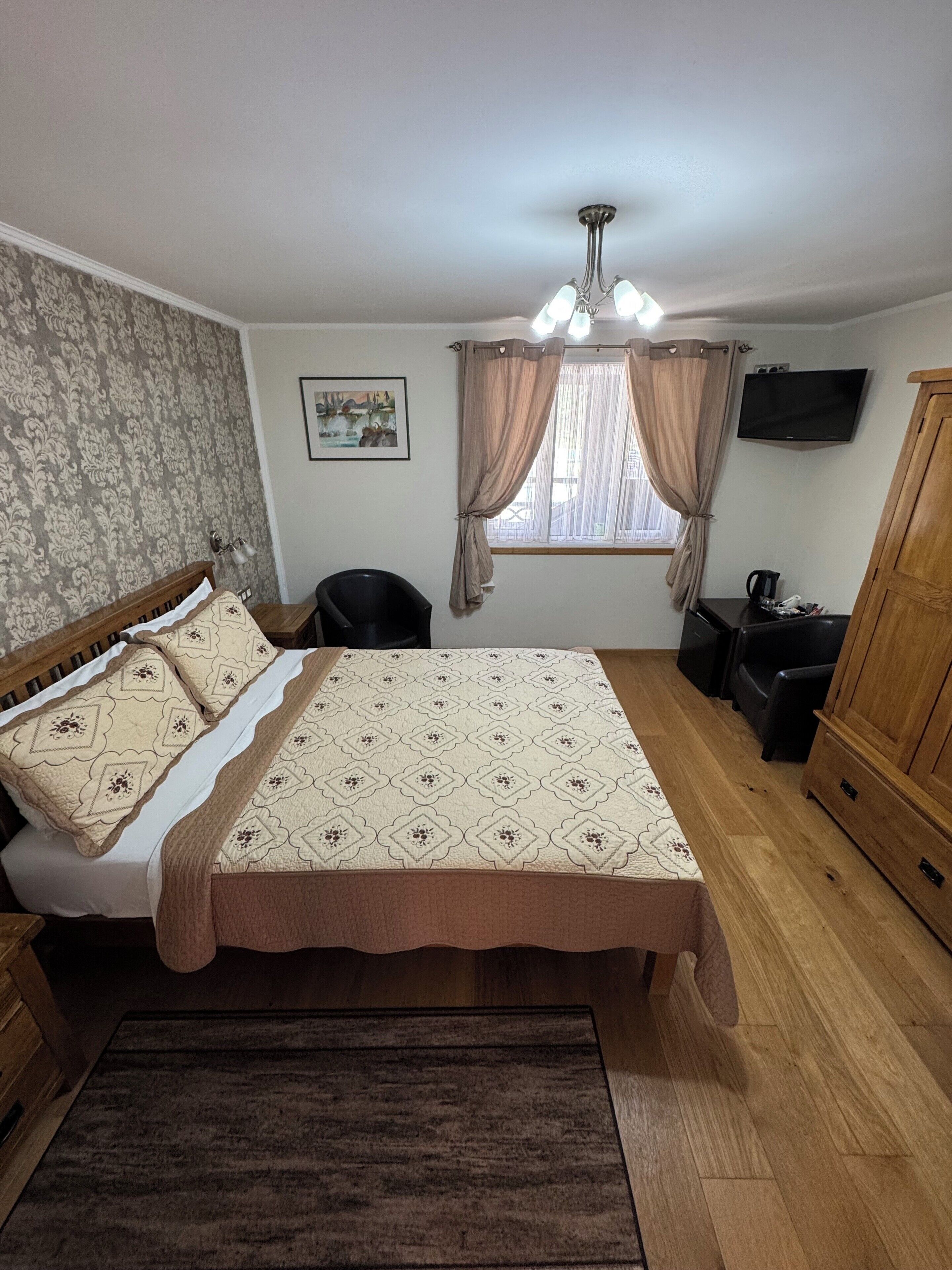 A bedroom with a bed, a desk, a chair, a TV, and a wardrobe.
