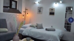 Een moderne slaapkamer met een bed, een bank, een vaas met bloemen en een wandlamp.