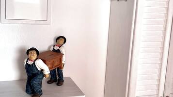A white wardrobe with a mirror above it and two figurines on a shelf.