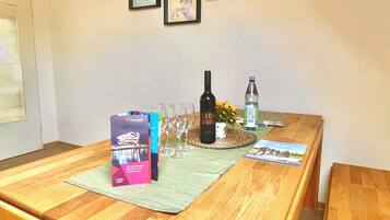 A wooden table with a placemat, wine bottle, glasses, a water bottle, and brochures.