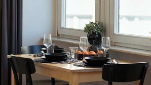 Uma mesa de jantar com cadeiras, uma janela com cortinas e um vaso de planta.