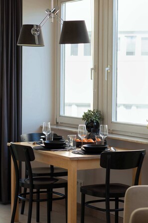 A dining table with chairs, a window with curtains, and a potted plant. - Spacious Apartment in the Center | Balcony | Castle (Szczecin)