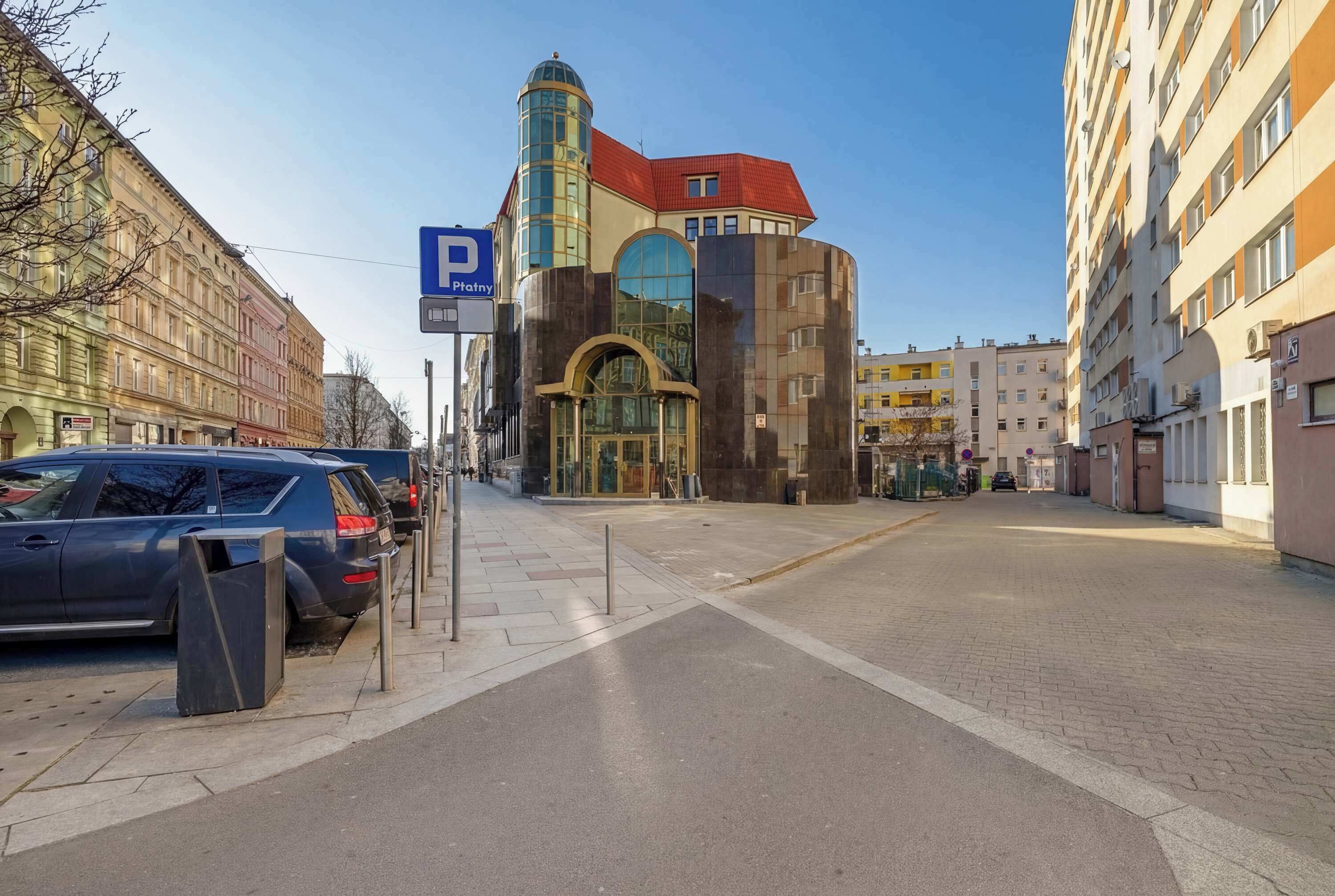 Une vue de rue avec un bâtiment dont la façade est caractérisée par une forme incurvée distinctive et dont le toit est rouge.