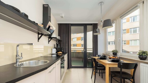Cozinha moderna com pia, fogão e área de jantar com cadeiras e mesa.