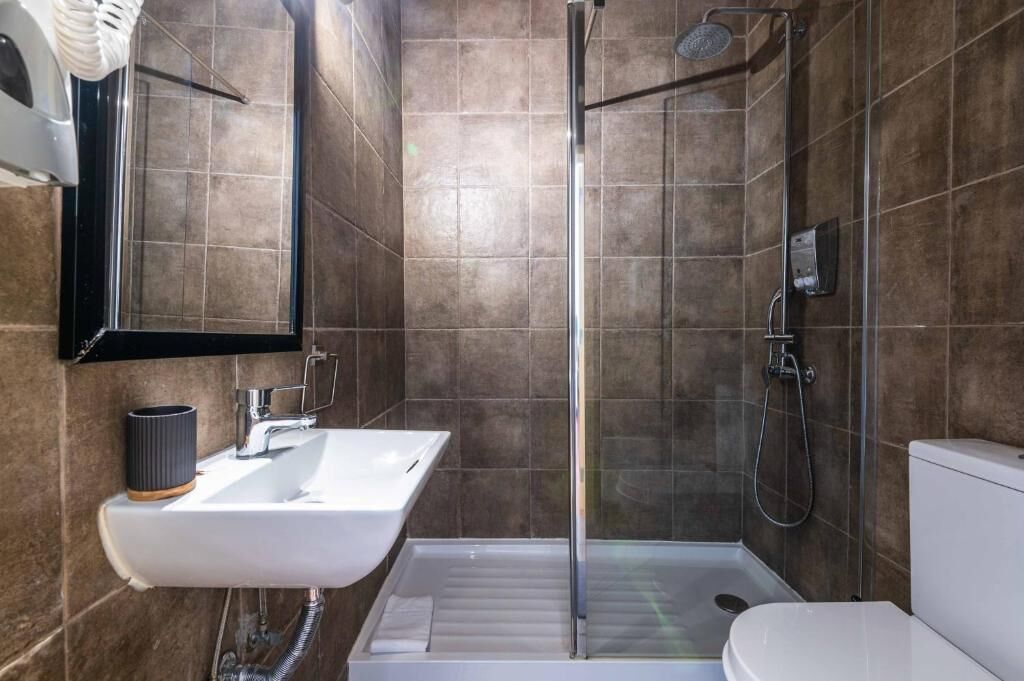 A modern bathroom with a shower, sink, and toilet.
