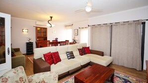 Ein Wohnzimmer mit einer Couch, einem Couchtisch und einem Essbereich im Hintergrund.