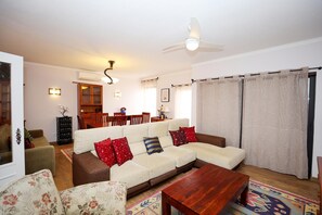 A living room with a sofa, coffee table, and a dining area in the background. - C27 - Torraltinha Way Apartment (Lagos)