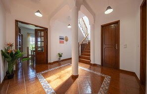 A spacious hallway with a tiled floor, a staircase, and a wooden door. - U 01 - Bedroom 1 in Casa Quinta Estação (Lagos)