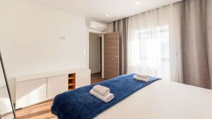 Una camera d'albergo moderna con un letto grande, un armadio a muro e un bagno visibile attraverso una porta aperta.