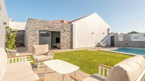 Una casa moderna con facciata in pietra, piscina e mobili da esterno.