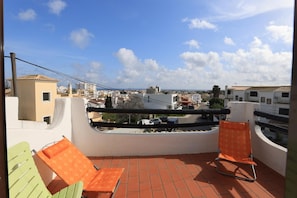 A balcony with two chairs, a view of a coastal town, and a clear sky. - B46 - Belavista Torraltinha Flat (Lagos)