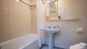 Une salle de bain comprenant une baignoire, un lavabo, des toilettes et un espace douche.