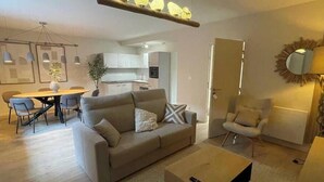 Uma sala de estar moderna com sofá, mesa de centro e área de jantar com cadeiras e mesa.