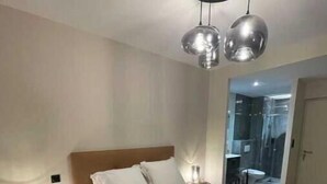 A bedroom with a bed, bedside tables, a headboard, and a ceiling light fixture. - Appart ' Hôtel "Pilote" - 4/6 Pers (Niergnies)