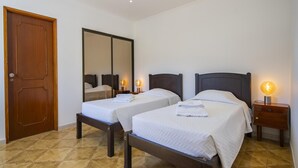 A hotel room with two beds, a wooden door, a large mirror, and bedside lamps.