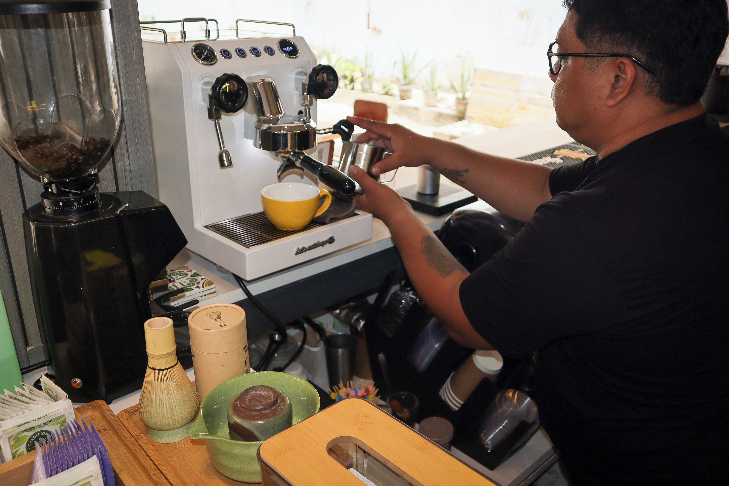 Une personne utilise une machine à café et prépare une tasse de café.