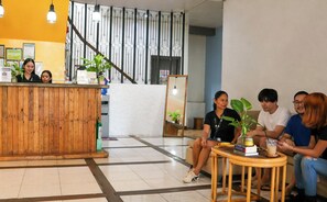 A reception area with a wooden counter, a staircase, and a seating area with a table and chairs.
