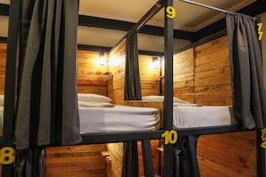 Habitación con literas, paredes de madera y cortinas, camas numeradas del 8 al 10, y una lámpara sobre la cama número 9.
