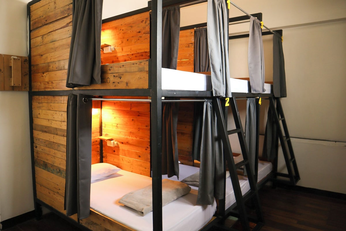 Habitación con literas, paredes de madera y cortinas.