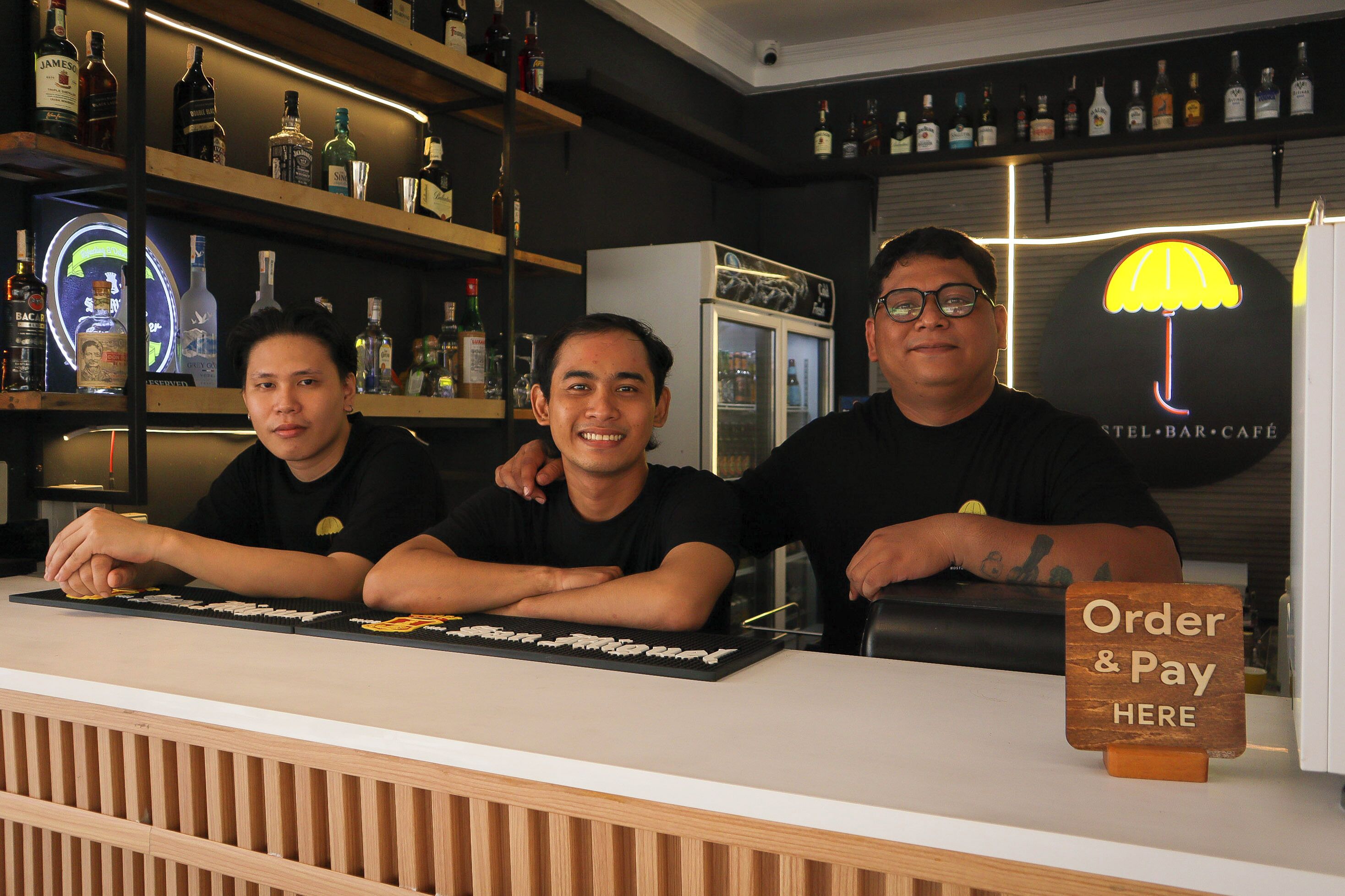 A bar area with a counter, shelves with bottles, and a sign indicating an order and pay area.