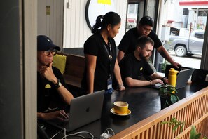 A group of people in a cafe setting with a laptop, a cup of coffee, and a yellow bottle on the counter. - Yellow Umbrella (Cebu City)